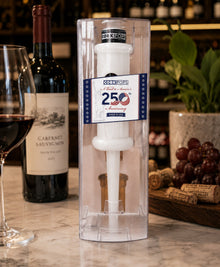 250th Anniversary Cork Pops opener in its clear tube beside a wine bottle