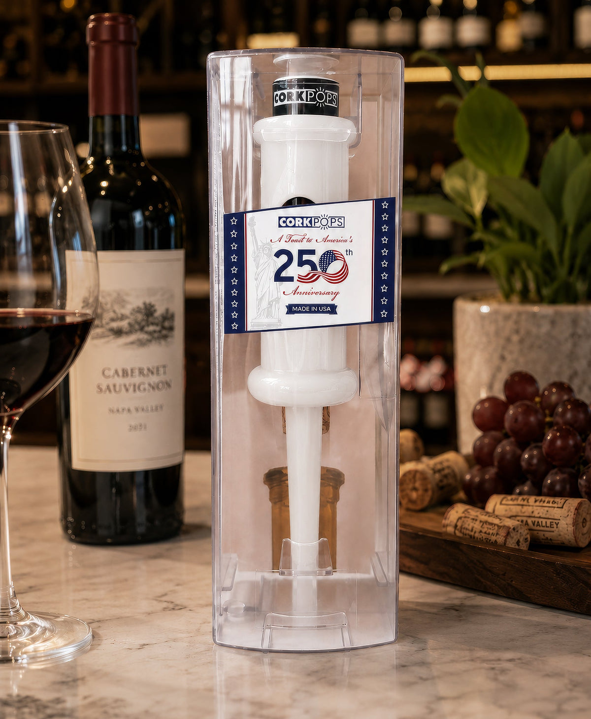 250th Anniversary Cork Pops opener in its clear tube beside a wine bottle
