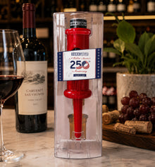 Red 250th Anniversary Cork Pops opener in packaging beside a wine bottle