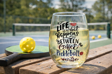 Printed wine glass on a pickleball court beside a paddle and balls