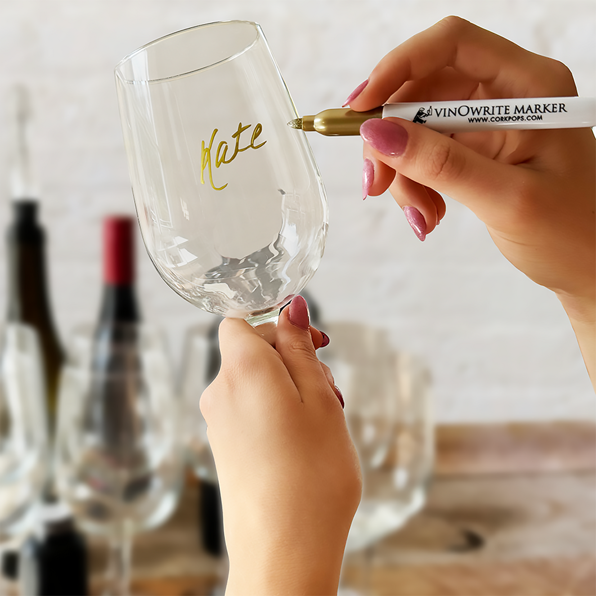 Hand writing on a wine glass with a gold vinOwriter marker