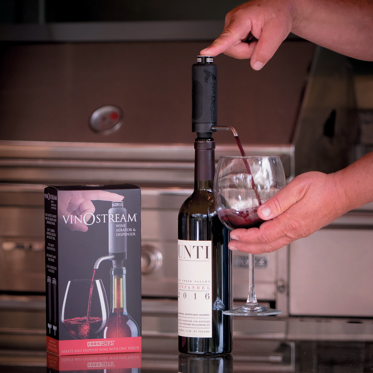 Hand pouring wine through a VinOstream dispenser on a bottle