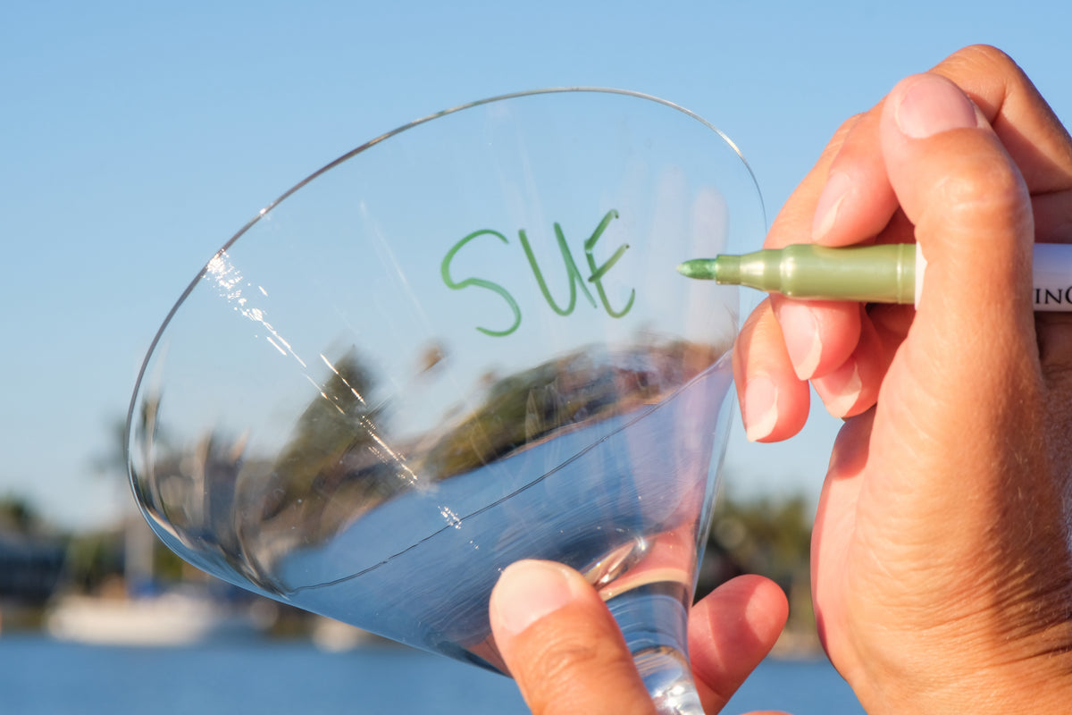 Hand writing a name on a wine glass with a vinOwriter marker