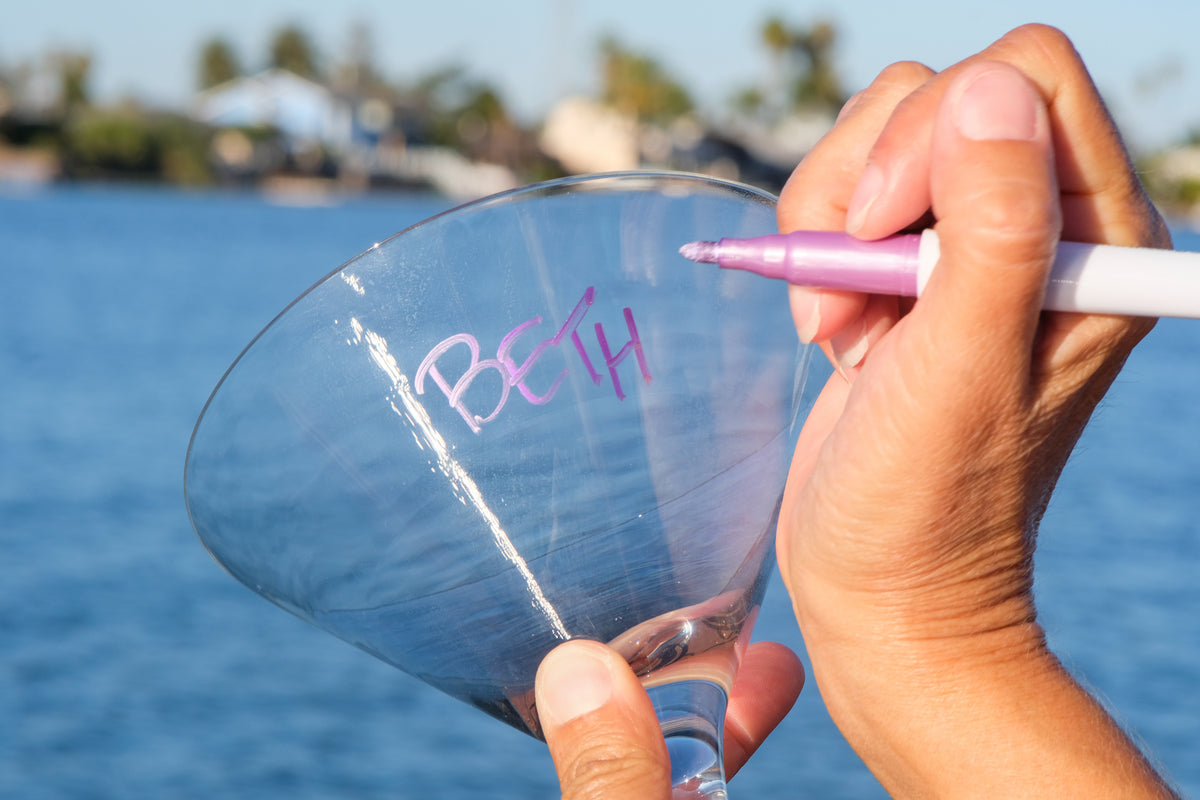 Hand writing on a wine glass with a pink vinOwriter marker